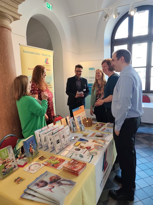 Von rechts: Herr Prof. Dr. med. René-Maxime Gracien (Leiter des Gesundheitsamtes Wies-baden) und Frau Milena Löbcke (Stadträtin) haben Sylvia Ohm und Elke Aryeequaye an ihrem Stand von Lebertransplantierte Deutschland e.V. begrüßt und ein Geschenk überreicht
